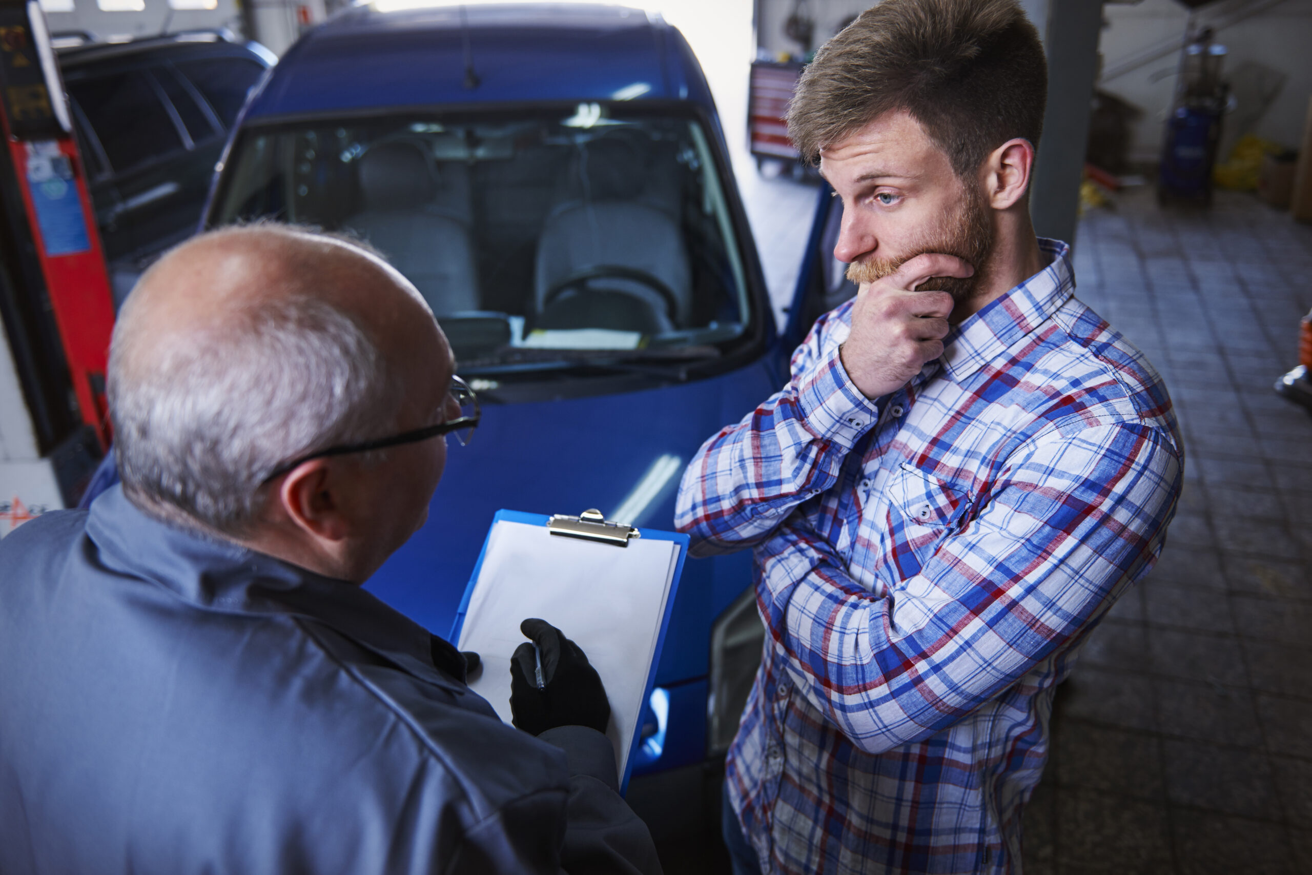 Customer talking with mechanic in workshop about genuine auto parts